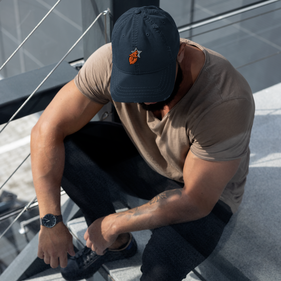 Man sitting on stairs wearing a navy dad hat with the wolfstar76 logo on it.