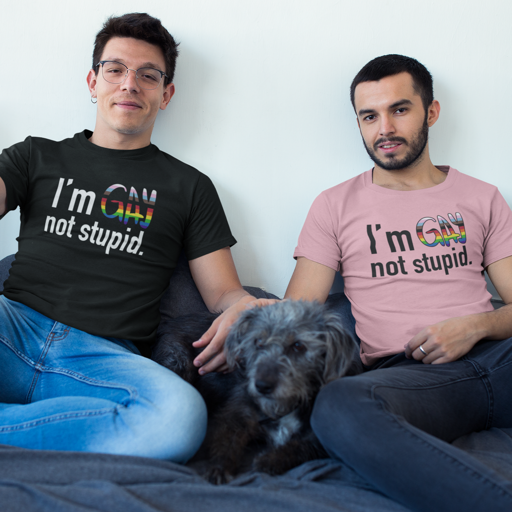 two men sitting on a bed with a dog both wearing a I'm Gay Not Stupid tshirt from thezacharymike