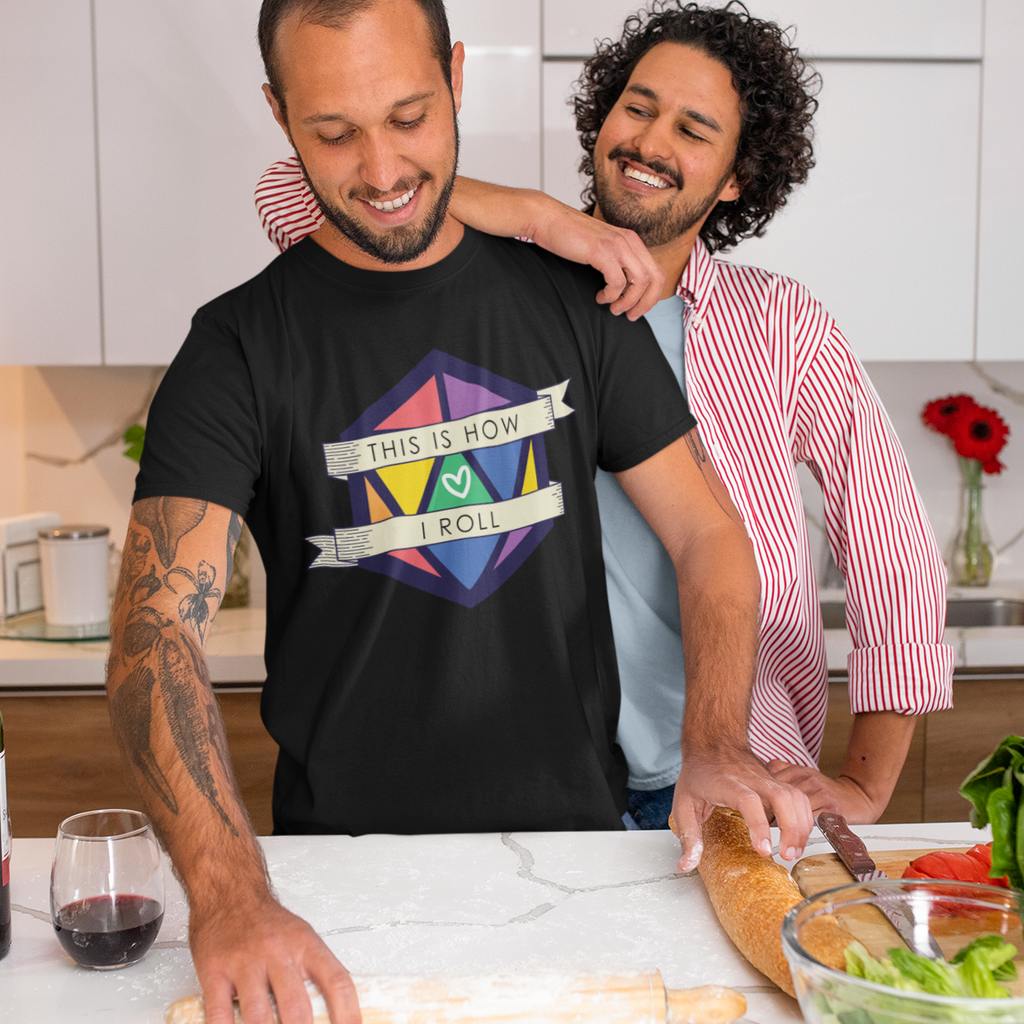 two men in the kitchen cooking, one wearing a black tshirt with the 2022 Pride D20 design from CalyxCreative