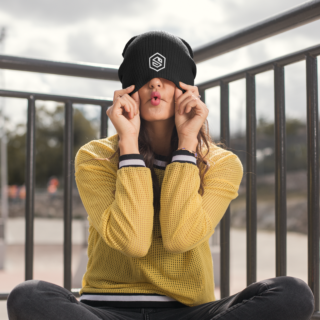a woman sitting down with a black beanie over her eyes and the serpentzn logo embroidered on it