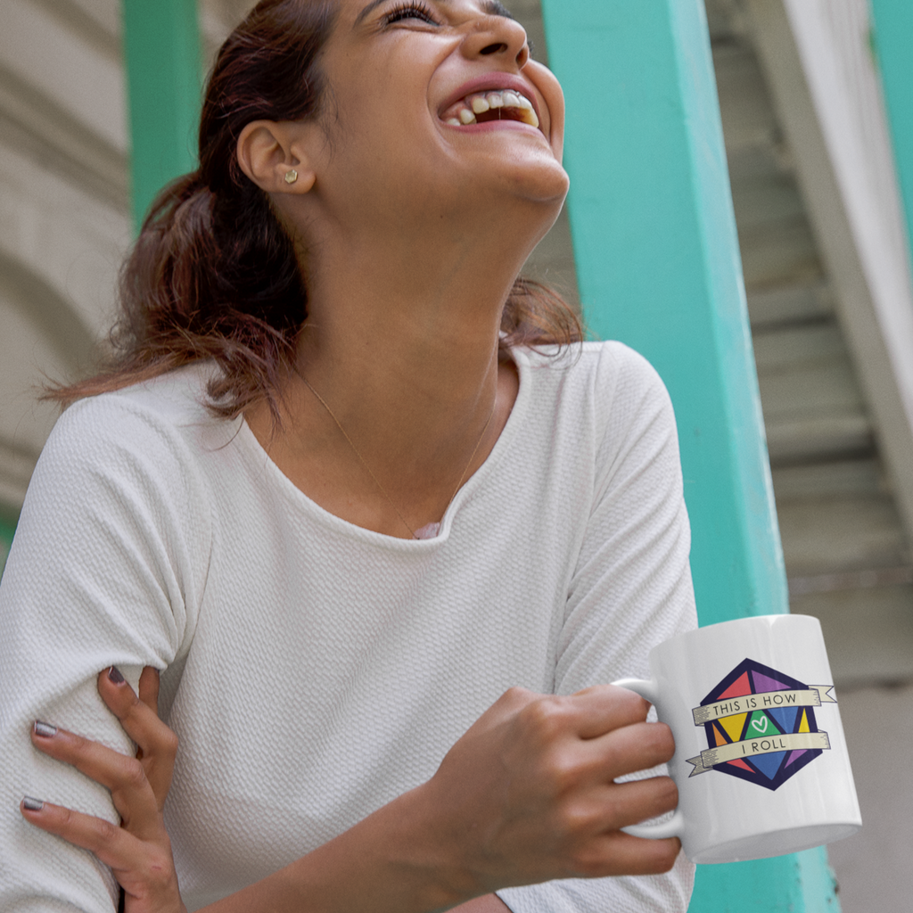 a woman standing on a balcony with a 2022 pride d20 mug from CalyxCreative