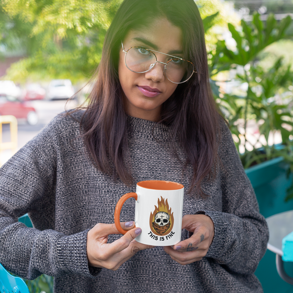 Woman with vintage glasses holding a mug with an orange handle with the halloween this is fine design on it.