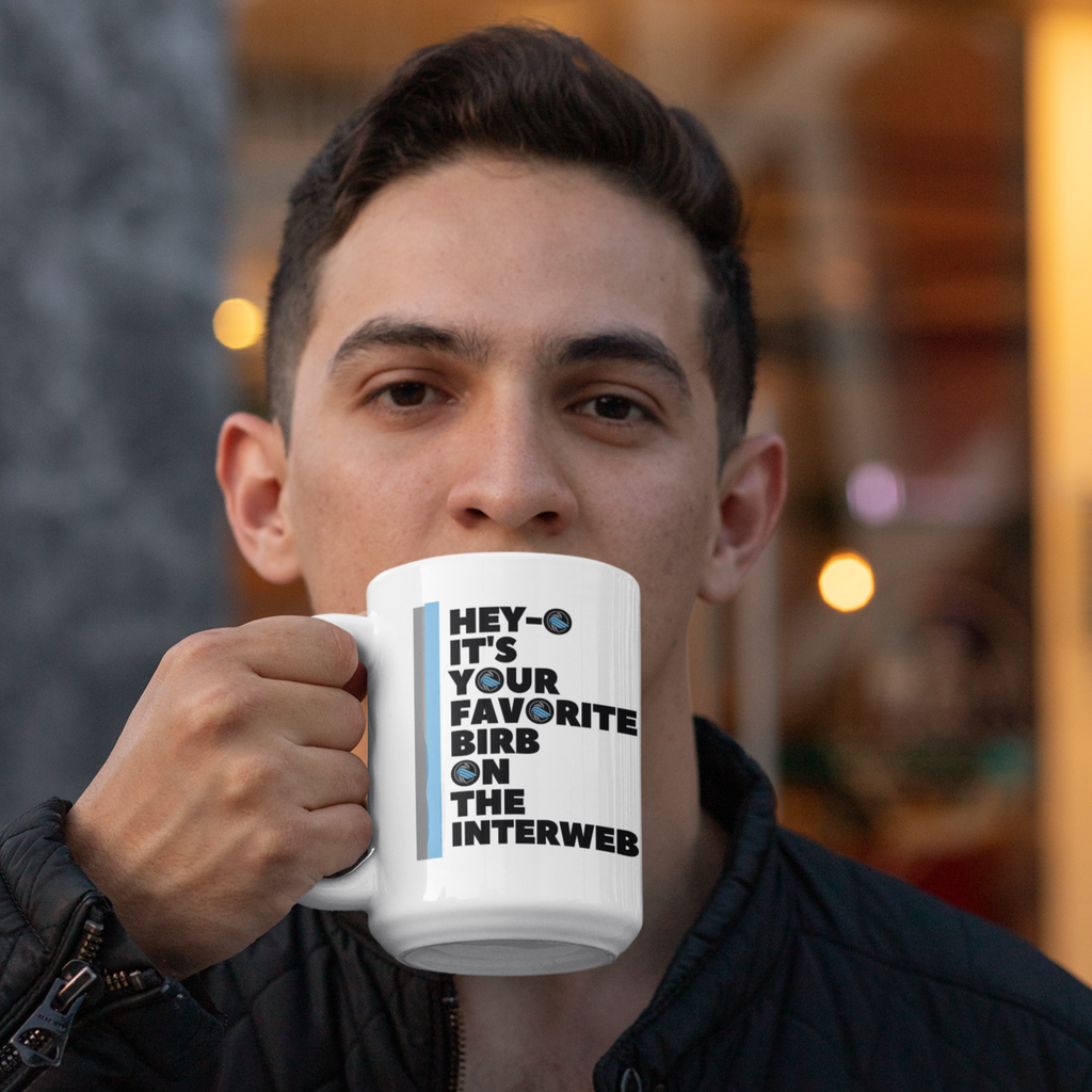 a man sitting outside a coffee shop taking a sip from a 15 oz favorite birb mug from aBlackSparrow