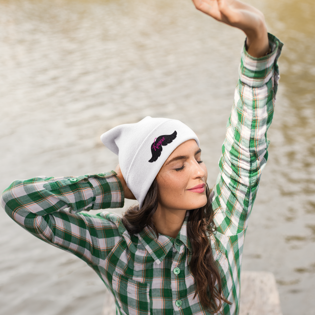 a woman  sitting by water wearing a white beanie with the moustache design by Koopa With A Moustache