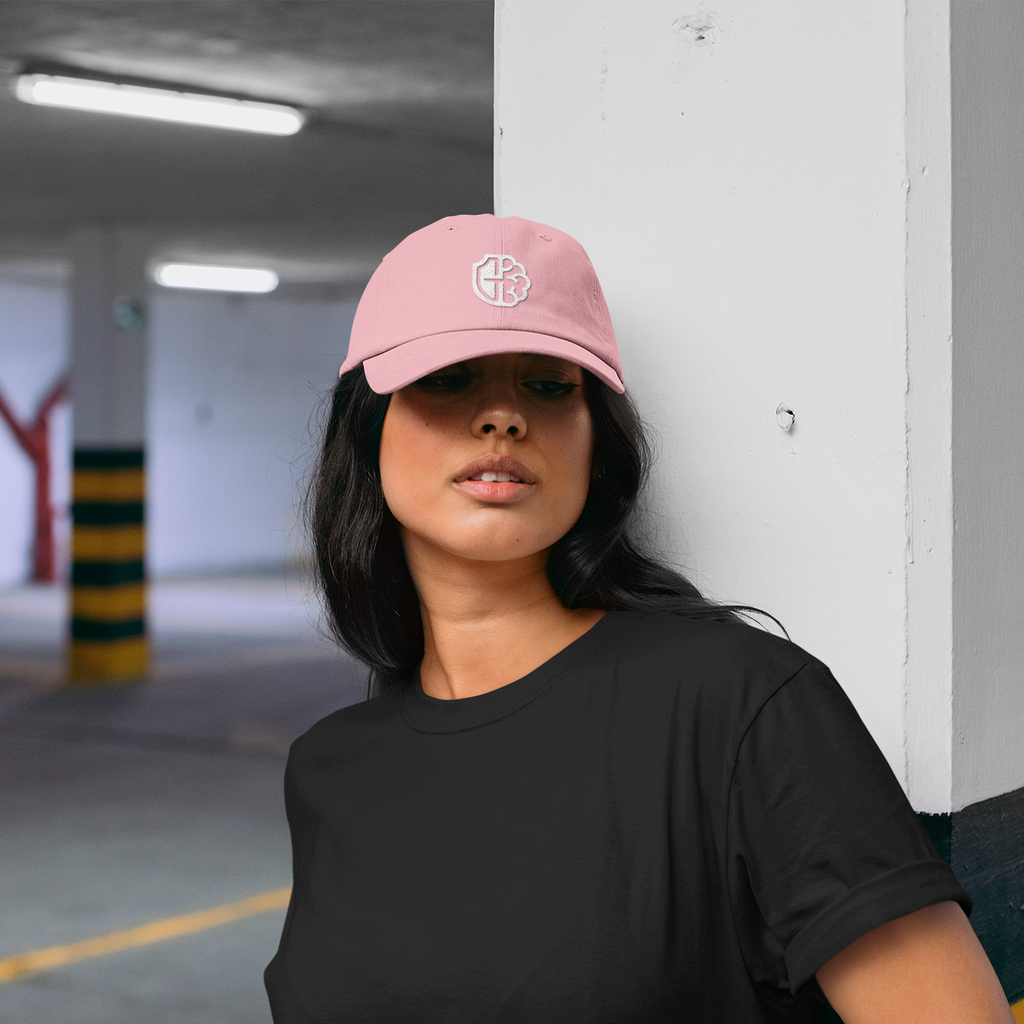 a woman wearing a pink dad hat with the guardians MH logo embroidered on it