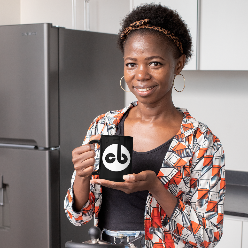 a woman holding a 15oz black mug with cbgray's logo in white on it