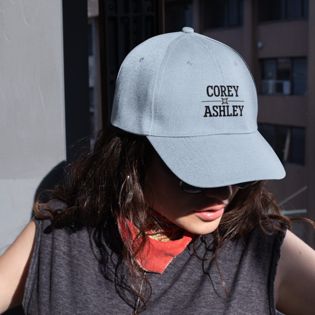a woman wearing sunglasses and a light blue dad hat with the corey and ashley wordmark