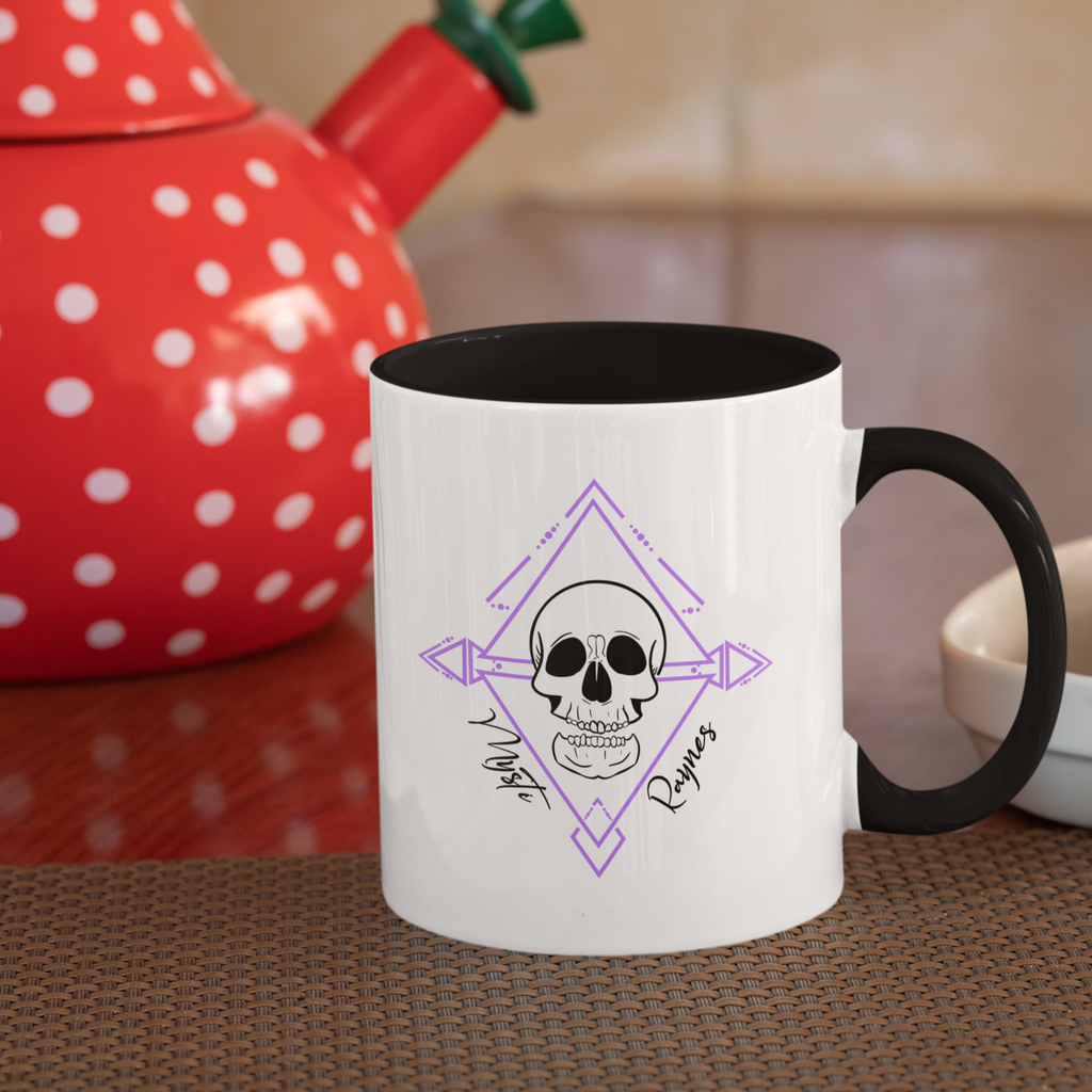 mug with black rim and black inside and the mysti raynes skull design on it, sitting in front of a red kettle