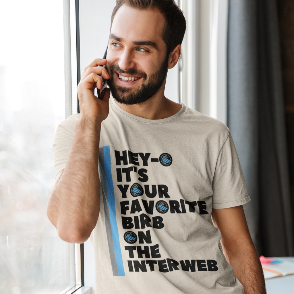 a man leaning against a window, talking on his cell phone, wearing a heather dust favorite birb tshirt from aBlackSparrow.