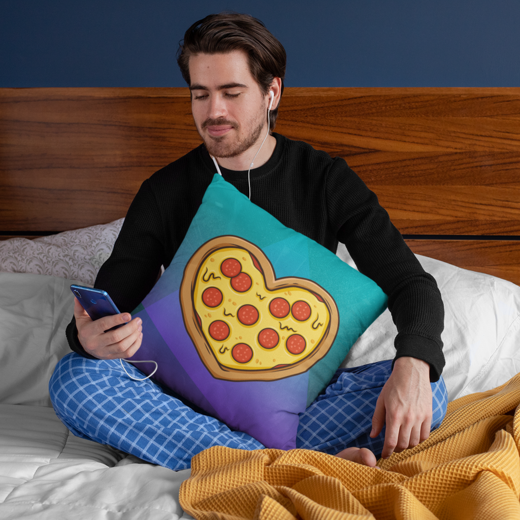 man sitting on his bed listening to music on his phone and holding the andrew fetch pizza heart pillow