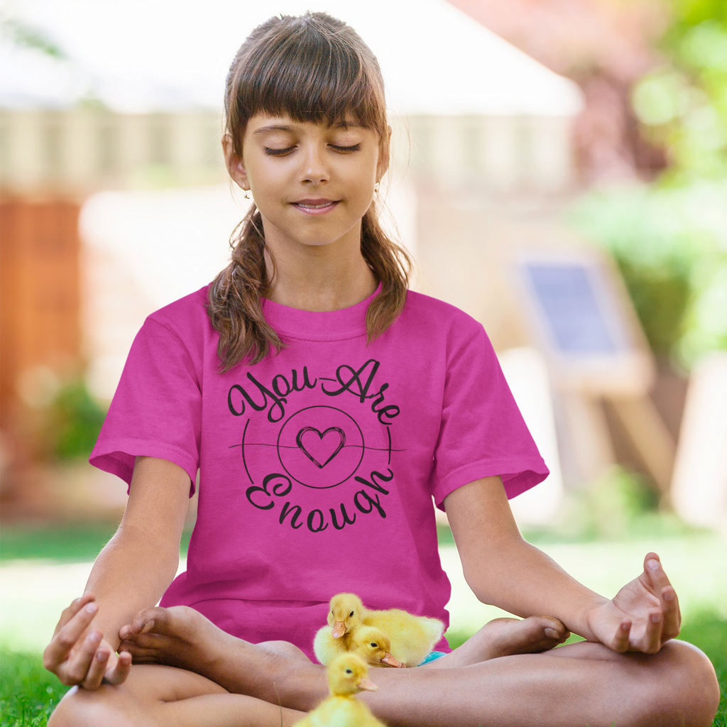 a girl sitting in a park meditating with ducks in her lap wearing a berry mystiraynes you are enough tshirt.
