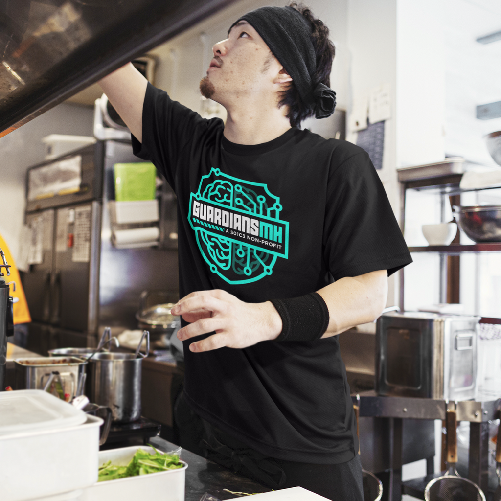 a man in a kitchen wearing a black guardians mental health shield tshirt