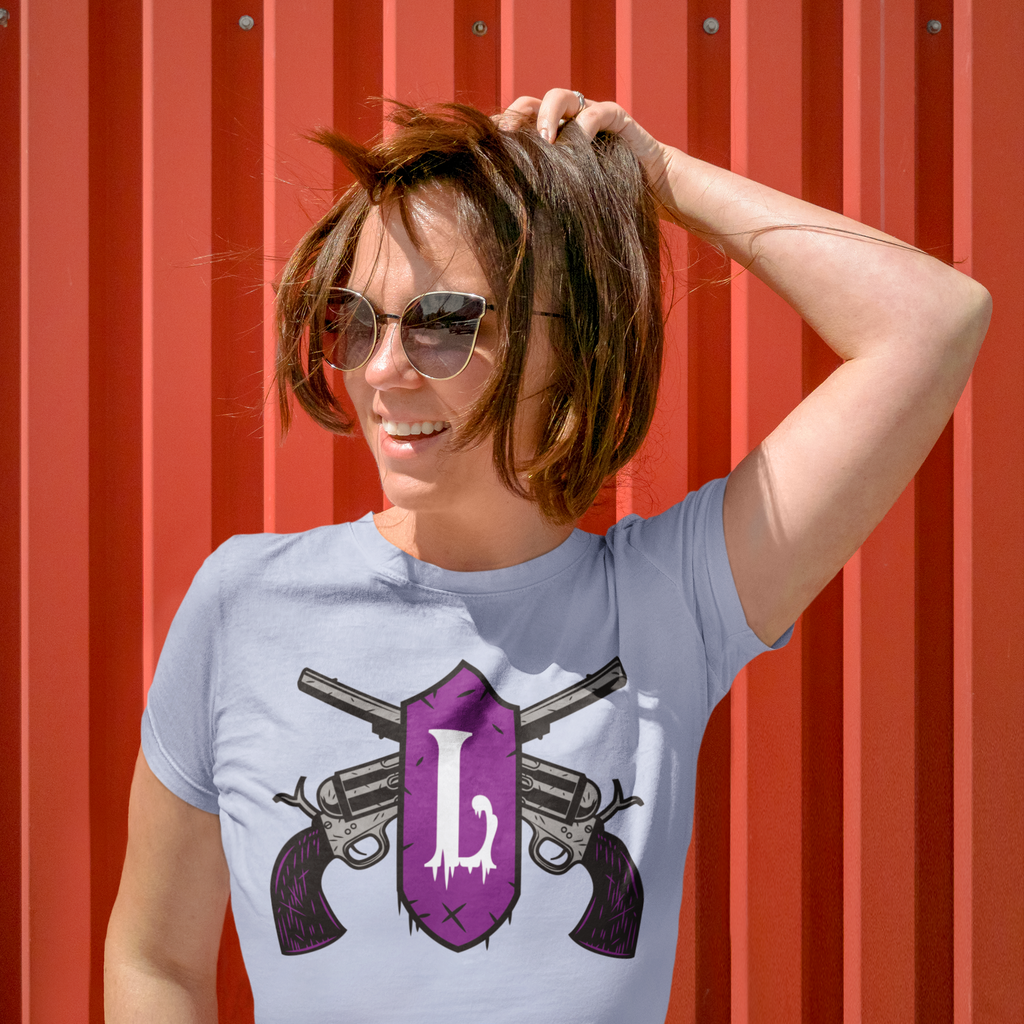A woman wearing sunglasses and holding her hair while wearing the heather blue ladgaman logo tshirt