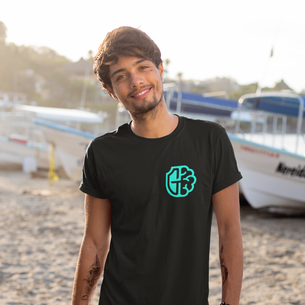 A man standing on the beach wearing a black tshirt with the guardians MH logo on the left chest